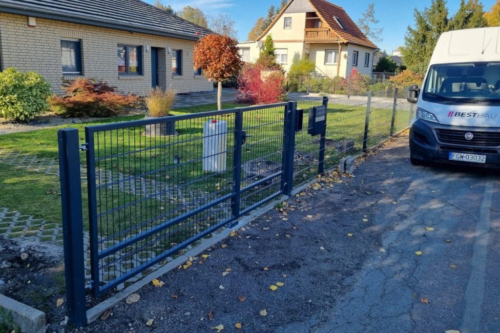 Metallzaun mit Tor und Pforte von BESTBAU ZÄUNE, installiert entlang einer Zufahrt vor einem Wohnhaus